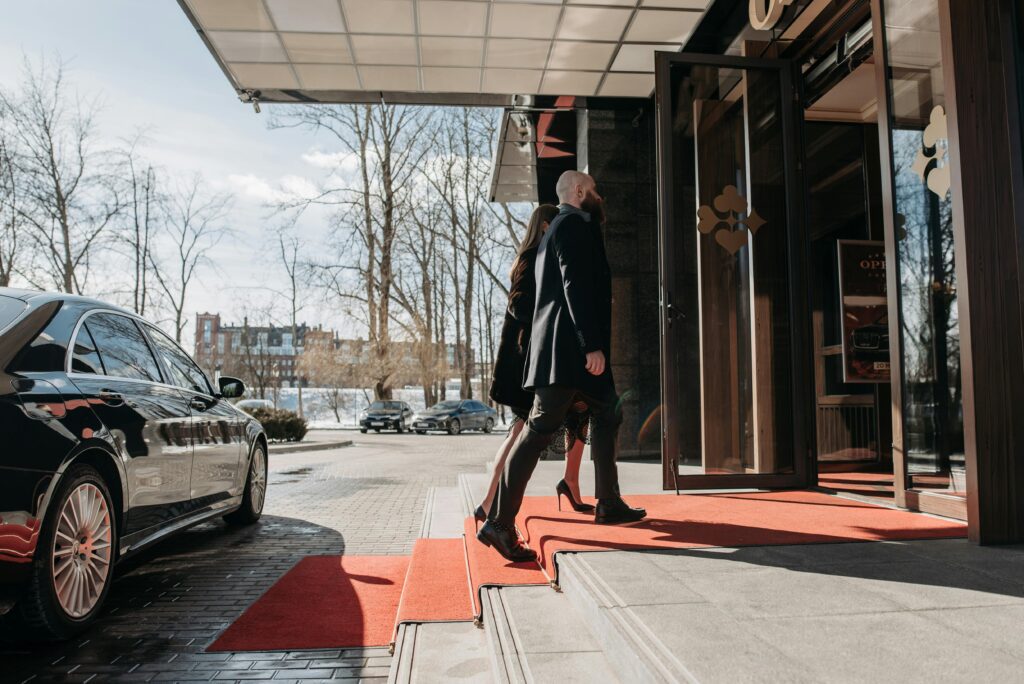 pexels photo 7594124 7594124 1 A man and woman elegantly dressed enter a luxury hotel, walking on a red carpet.